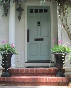 two black planters on the front steps of a house