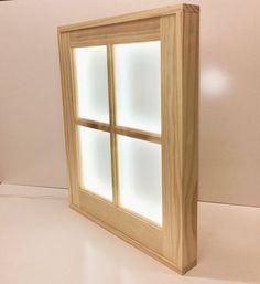 a wooden window with three panes on the outside and one in the inside, against a white wall