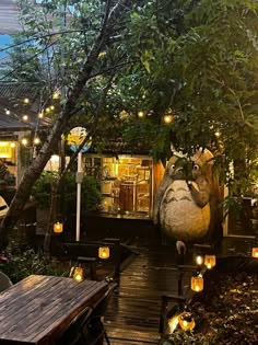 an outdoor restaurant with lit candles and stuffed animals on the outside wall, surrounded by greenery