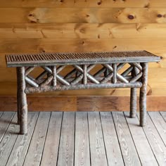 a wooden bench sitting on top of a hard wood floor next to a log wall