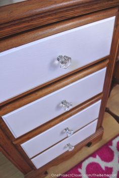 a close up of a white dresser with wood trimmings and knobs on the drawers