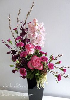 a black vase filled with pink and purple flowers