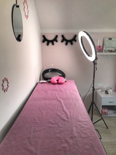 a room with a pink bed, mirror and light on the wall next to it