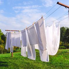 several white clothes hanging on an electric line in the grass with blue sky and clouds behind them