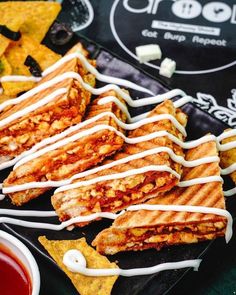 grilled sandwiches with white icing on a plate next to tortilla chips