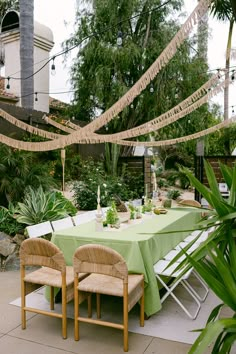 an outdoor dining area with green table cloths and wicker chairs set up for a party