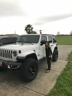 a woman standing next to two white jeeps