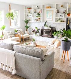 a living room filled with furniture and lots of plants on the wall above it's fireplace