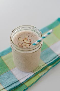 a smoothie with almonds is in a mason jar on a green and white checkered napkin