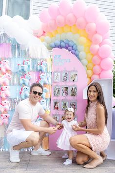 a man, woman and child posing in front of a candy shop with balloons on the wall