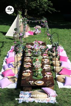 an outdoor picnic table with pink and white decorations on it, including plates and bowls