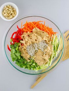 a glass bowl filled with veggies and sauce on top of a white table