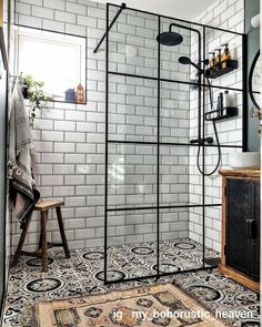 a bathroom with black and white tiles on the floor, shower head, and rug