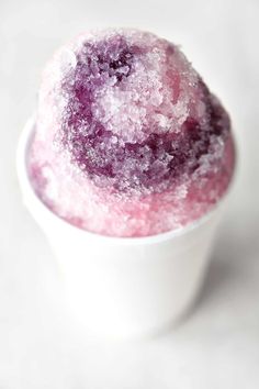 a white cup filled with purple sugar on top of a table