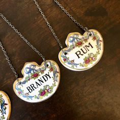 three necklaces with the words brandy and rum on them hanging from metal chain chains