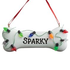 a dog bone ornament decorated with christmas lights and the words sparky on it