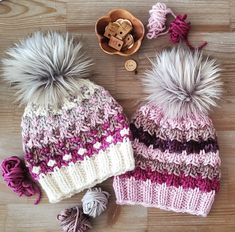 two knitted hats with pom - poms sitting on top of a wooden floor