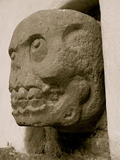 a stone head on the side of a building with a hole in it's wall