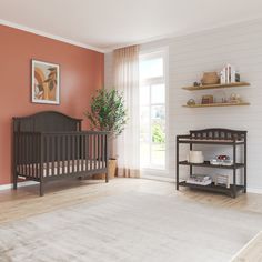 a baby crib in the corner of a room with an orange wall and wooden floors