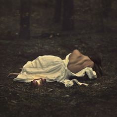 a woman is laying on the ground with her head down and wrapped in a white cloth