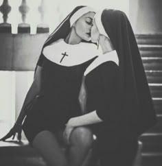 black and white photograph of woman in nun outfit sitting on the steps with her head down