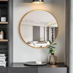 a round mirror is hanging on the wall above a dresser with a potted plant