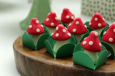 small red mushrooms are sitting on top of green leaves and paper cones in the shape of trees