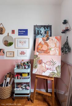 an easel in front of a painting on the wall with other art and craft supplies