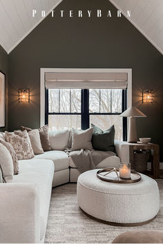 a living room filled with furniture and a large window covered in windows next to a white ottoman