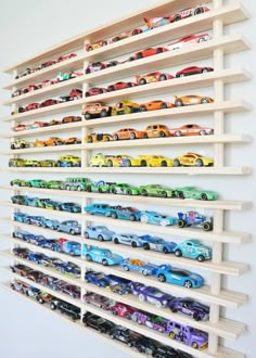 a wall mounted shelf filled with lots of toy cars