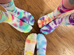 four people with colorful socks standing in a circle on a wooden floor and looking at the camera