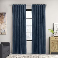 a living room with a couch, chair and window covered in dark blue velvet curtains