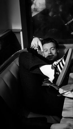 a man sitting on top of a couch next to a table with a book in front of him