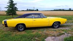 a yellow muscle car parked in a field