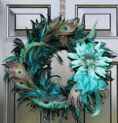 a wreath with peacock feathers and blue flowers on the front door, hanging from a chain