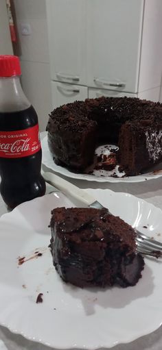 two plates with chocolate cake on them and a bottle of coca - cola in the background