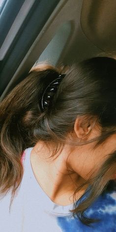 a woman with her head in the back seat of a car, wearing a hair clip