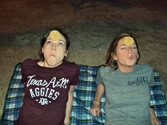 two women laying on a blanket with their faces covered by yellow paper covering their eyes