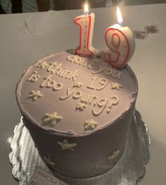 a birthday cake with two lit candles on it and the number 19 written in frosting