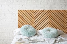 two balls of yarn sit on top of a bed next to an open book in front of a wooden headboard