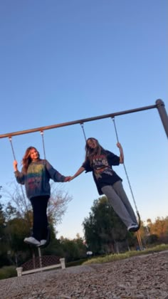 two girls are swinging on a swing set