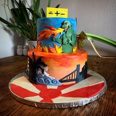 a multi - layered cake decorated with cartoon characters on top of a wooden table next to a potted plant