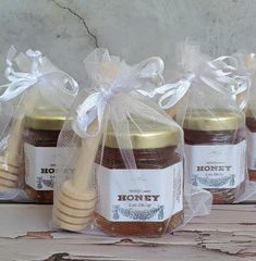 three jars of honey wrapped in cellophane and sitting on a table with a wooden spoon