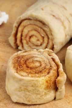 two cinnamon rolls on a cutting board next to an apple and some other food items