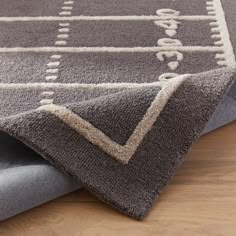 a close up of a rug on a wooden floor with a wood table in the background