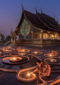 a building with many lit candles in the middle of it at night, surrounded by an intricate circular design