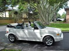 a white convertible car parked in front of a tree