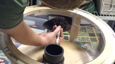 a man is working on something in a round glass case with wood trimmings