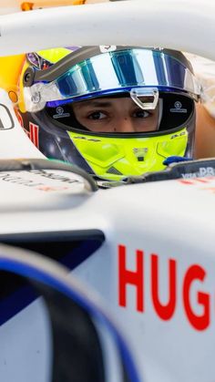 a man sitting in a racing car wearing a helmet