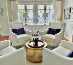 a living room filled with white furniture and windows